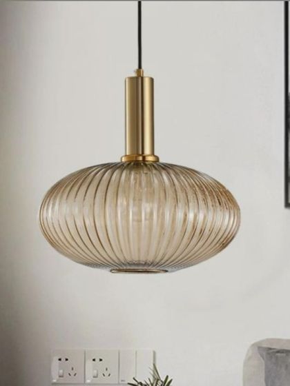 The Cordelia pendant in a cognac glass finish with an elegant oval shape. The ribbed glass texture beautifully diffuses the light, making it a perfect Nordic-style hanging light for a restaurant or dining area.