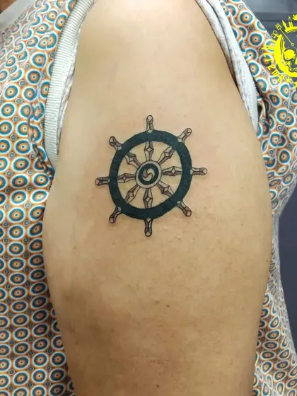 A ship's helm or Dharma wheel tattoo on the shoulder. This is a simple, bold-lined symbol of guidance, direction, and following one's path.