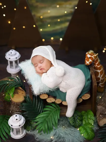 A cozy woodland adventure theme, with a baby in a warm knit outfit sleeping on a log bed, surrounded by lanterns and forest greenery.