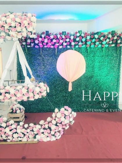 A clean and modern take on the crescent moon theme. This setup uses soft pink and white flowers against a green wall, perfect for a contemporary naming ceremony.