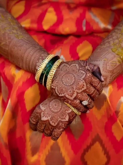 A close-up of the bride's hands, showcasing the intricate mandala design and the excellent color of the henna stain.
