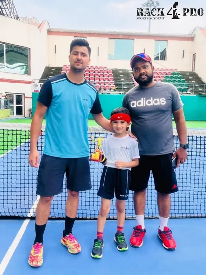 A champion with his coaches. This photo highlights the strong bond between our players and the coaching staff who guide them to victory.