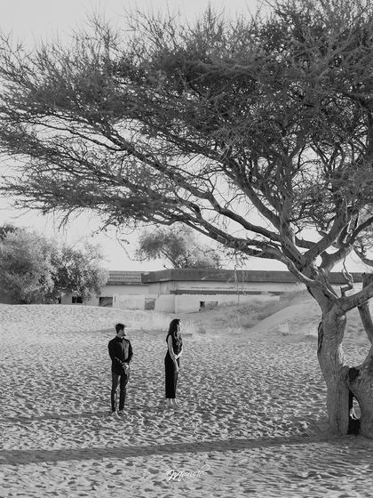 A dramatic black and white landscape shot, placing the couple in the vast, beautiful expanse of the desert.