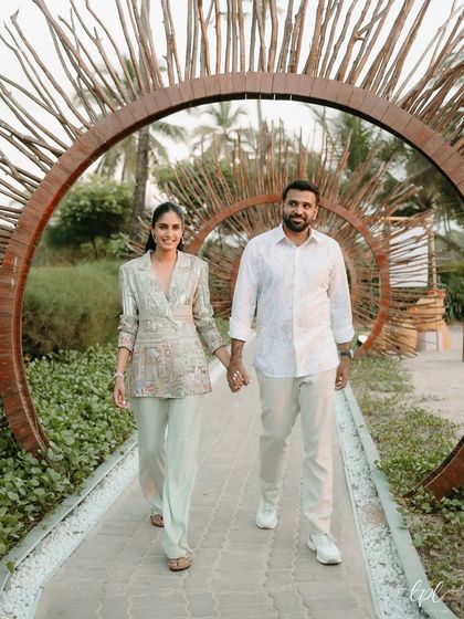 The happy couple walking through a custom-designed driftwood archway at their Goa beach event. This natural, sculptural entrance perfectly complemented the seaside location.