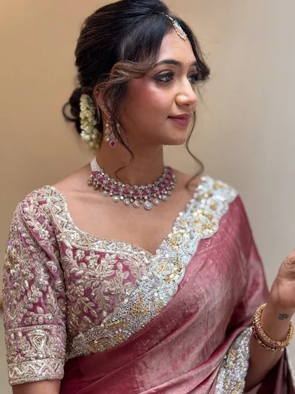 For me, modern elegance is about clean lines and a soft glow. I created this look for Monica's reception, focusing on a flawless base, defined eyes, and a romantic, messy hair bun that perfectly complemented her designer saree.