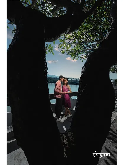 A creative shot, framing the couple between the branches of a tree. It adds an artistic touch while still capturing a natural, candid moment between them.