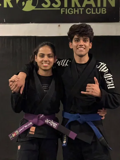 A journey marked by dedication. Anwesha celebrating her purple belt promotion with a teammate. These milestones are shared by the whole family.