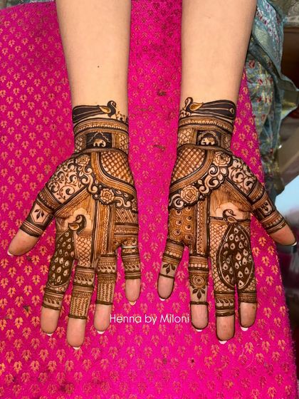 A classic, full-coverage bridal mehendi with a mix of geometric patterns, floral work, and traditional figures. The symmetry across both hands creates a balanced and regal look.