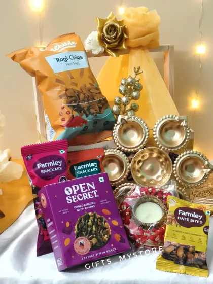 A closer look at the contents of our wooden crate hamper. It includes healthy snacks like Open Secret nutty cookies and Farmley date bites, along with a set of beautiful diyas.