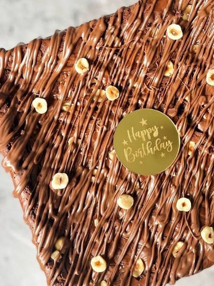 Another look at a custom birthday brownie slab. This one is loaded with a Nutella drizzle and toasted hazelnuts for a rich, nutty flavor in every bite.