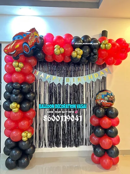 A simple car-themed balloon arch for a home party. The red and black balloons are accented with a car foil balloon and a shimmer curtain.