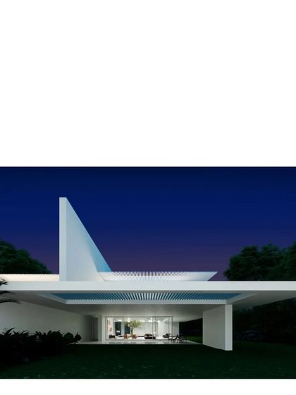 The sculptural form of the Koba House at dusk. The design is elemental, using clean white planes and a dramatic roofline to create a powerful statement against the deep blue sky.