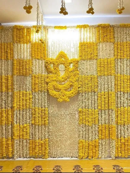 For a Haldi ceremony at home, I designed this full feature wall using a checkerboard pattern of yellow and white marigolds. The centerpiece is a Ganesha motif made entirely of fresh yellow marigold flowers, making it a perfect photo backdrop.