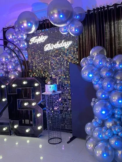 A full view of the modern 23rd birthday party setup, with large marquee numbers, a silver sequin wall, and dramatic silver chrome balloon garlands.