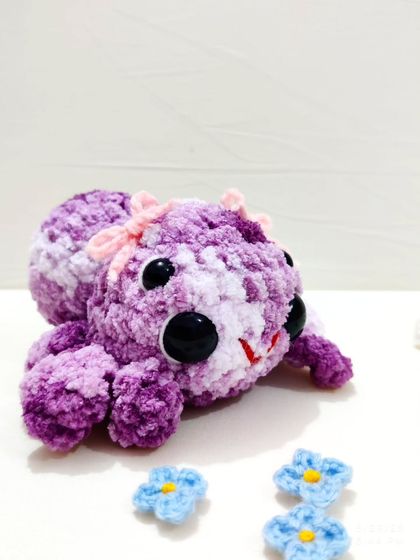 A close-up on the giant, friendly eyes of the spider plushie.