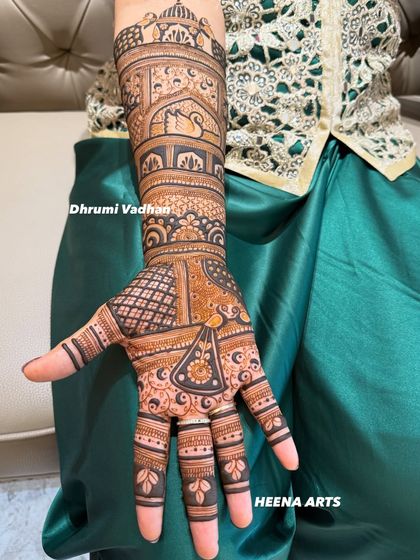 A single-hand view of a detailed design, showing a mix of jaali (net) patterns and figurative work like swans.