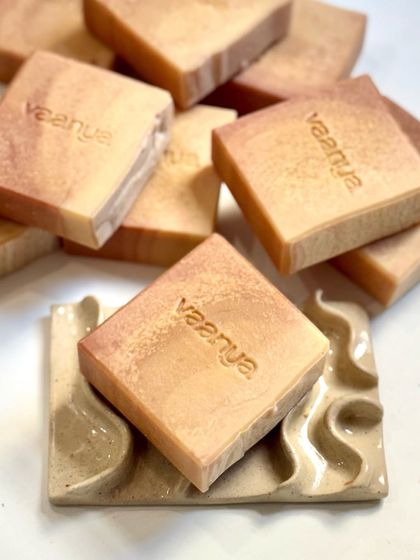 One of our custom sunset soaps resting on a beautiful ceramic soap dish. The warm orange and pink tones are so inviting.