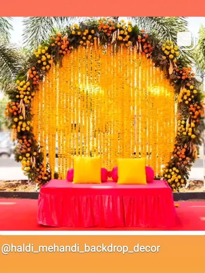 A classic Haldi backdrop with a large ring made of marigolds and a screen of genda phool strings. The simple yet elegant low seating with bright yellow cushions completes this traditional look.
