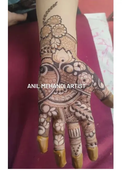 A close-up of a palm filled with intricate traditional mehandi. The design includes a central circular element with detailed shading and is surrounded by floral and paisley patterns.