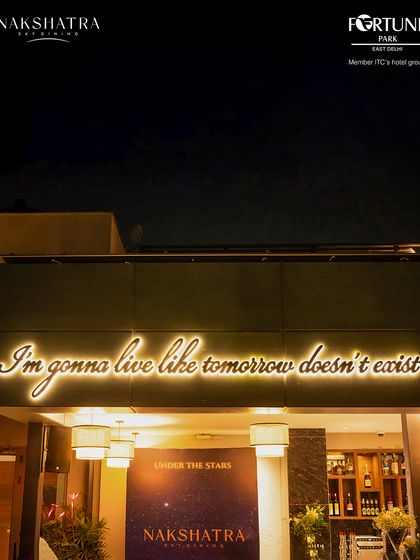 The motto of our rooftop bar, glowing against the night sky, inviting guests to enjoy the moment.