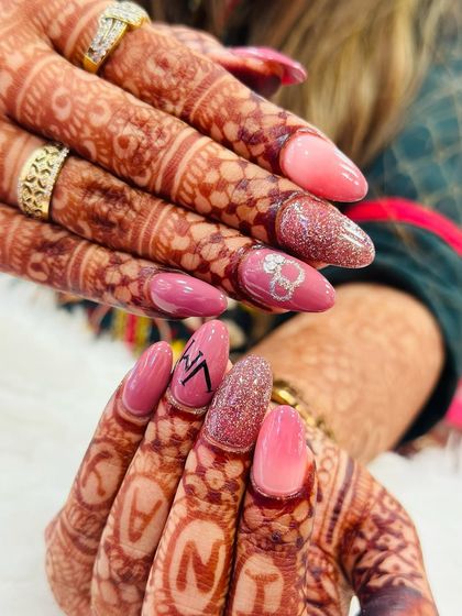 The perfect personalized bridal set. These nails feature a mix of pink ombre, sparkling glitter, and custom hand-painted initials of the bride and groom. It's a beautiful way to add a personal touch to wedding nails.