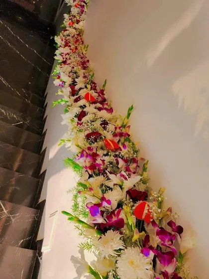Another view of the staircase wall decoration, with a mix of white, red, and purple flowers.