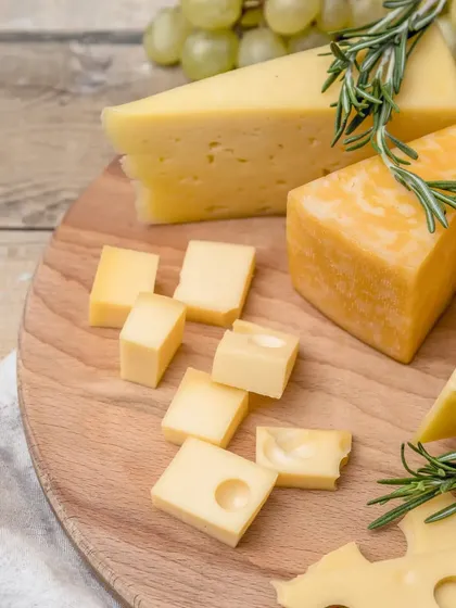 A showcase of different cheese varieties. This image highlights the unique textures and characteristics of Swiss, cheddar, and other hard cheeses, garnished with fresh rosemary.