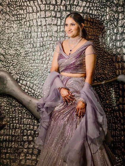 A stylish portrait of the bride against a textured silver wall. Her confident pose and chic sangeet outfit create a striking image.