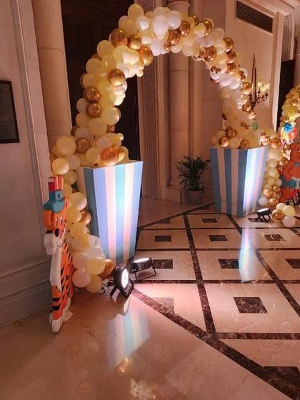 A balloon archway with striped pedestals, part of a larger carnival-themed event decoration.