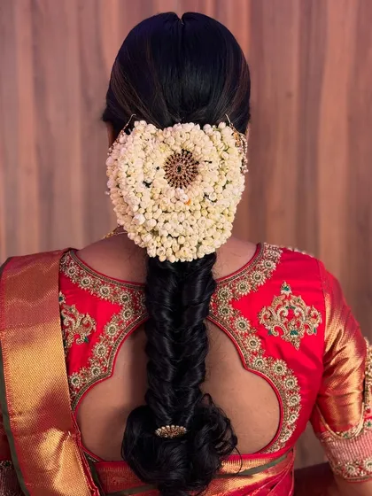 Bridal hairstyling is just as important as the makeup. Here is a detailed look at a classic South Indian fishtail braid, intricately woven with fresh jasmine flowers and a statement floral piece, perfect for a traditional wedding ceremony.