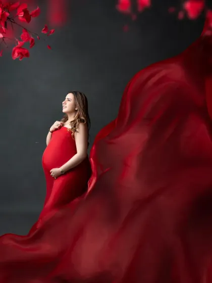 A classic maternity portrait with a dramatic flair. The expectant mother looks radiant in a red gown, with the fabric elegantly tossed to create beautiful, flowing lines.