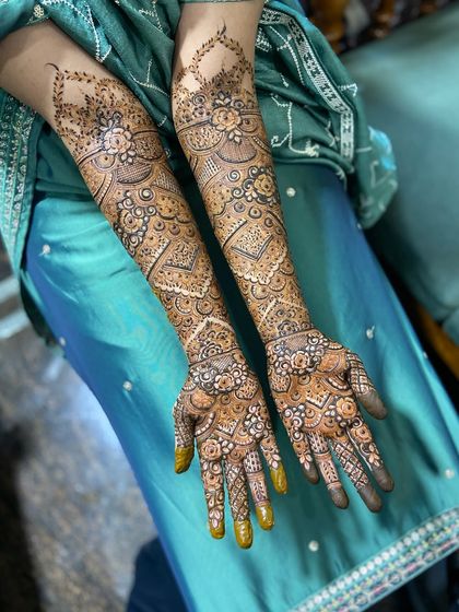 A wide shot displaying the full length of the bridal mehendi on both arms. This level of coverage is perfect for making a statement on your wedding or engagement day.