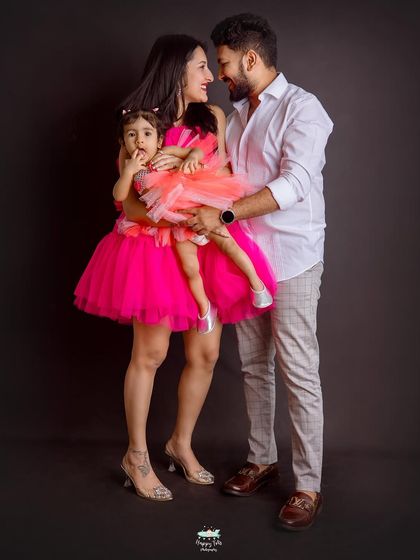 We love a pop of color. This family's vibrant pink outfits look stunning against the dark backdrop, creating a bold and beautiful family portrait.