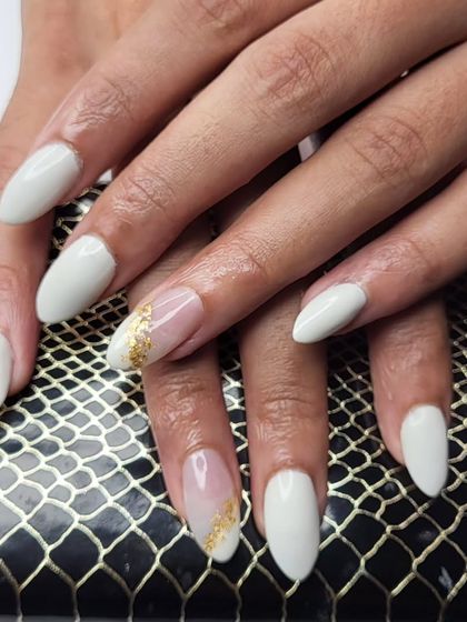A simple yet elegant design. These white almond-shaped nails are accented with a swipe of gold foil for a touch of modern glamour.