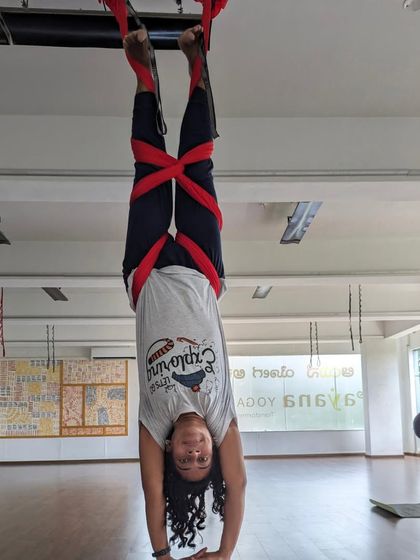 A student holds a supported handstand, demonstrating the strength and stability gained through consistent practice.