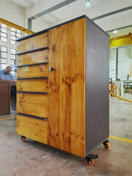 A three-quarter view of the mobile storage cabinet, highlighting the contrast between the natural pine door and the grey side panel.
