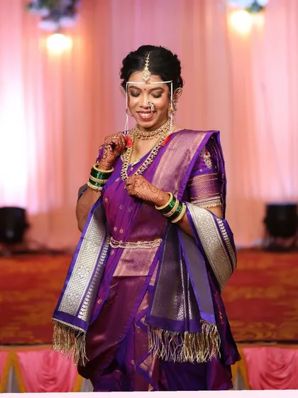 The bride adjusting her nath, a classic pose. The makeup highlights her features beautifully.