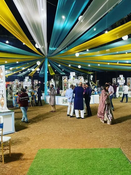 A wide view of a large outdoor event with a blue and yellow draped canopy. This shows how I can manage large-scale decor to create a vibrant and cohesive theme across a big space.