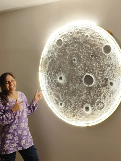 A happy student pointing to the large moon art she helped create.