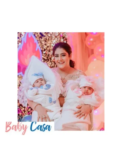 Double the joy, double the love. A mother holds her twin babies, each snuggled in their own personalized and coordinated coming home wraps, one in blue and one in pink.