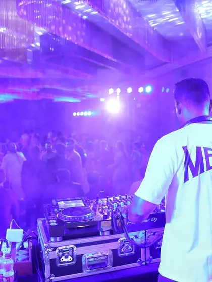A view from behind the console, looking out at a packed corporate party. The custom 'Mervin' shirt is part of my professional branding for events.