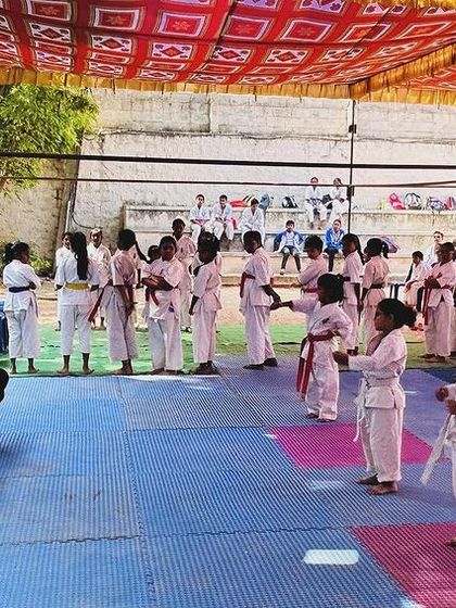 Students waiting for their turn to compete. The discipline learned in the dojo is visible even when they are not fighting.