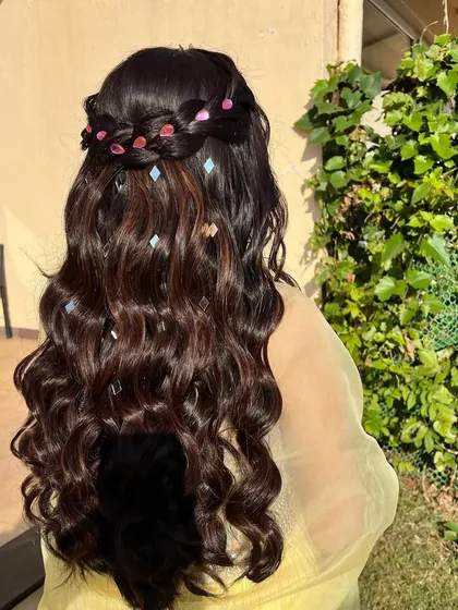 A simple yet stunning hairstyle for a daytime event. The half-up braid is decorated with pink and silver accessories for a touch of color and shine.