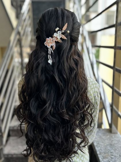 A beautiful half-up, half-down style with soft waves, adorned with a delicate, modern floral hairpiece.