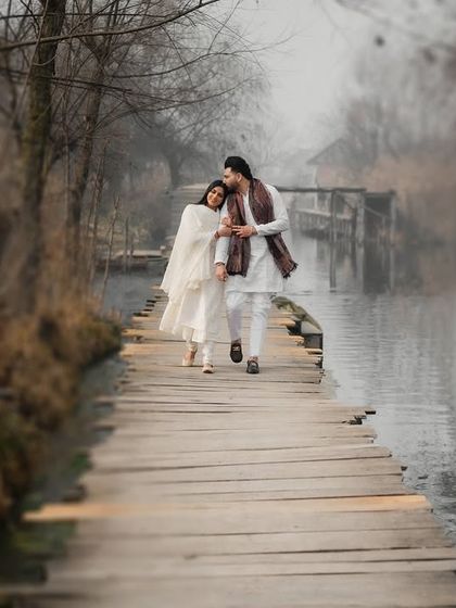 A tender moment while walking along a narrow wooden path by the water in Kashmir. The composition leads the eye to the couple, creating a feeling of intimacy and shared journey.