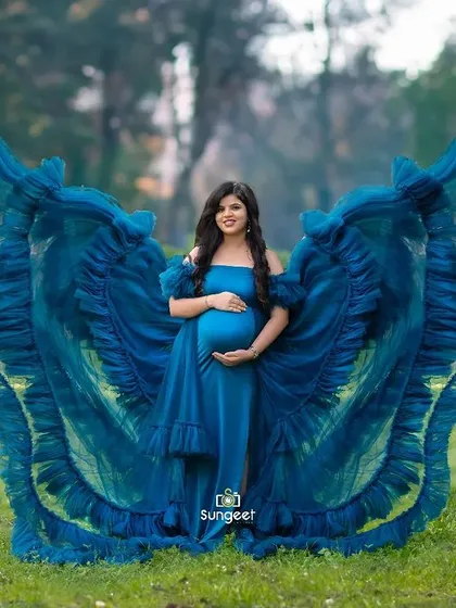 An outdoor shot where the vibrant blue gown creates a stunning butterfly effect against the lush green background of the park.