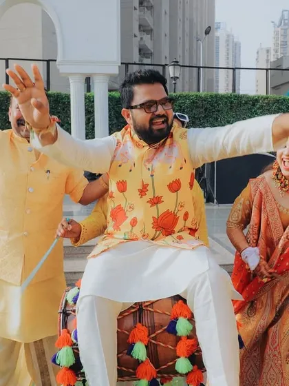 The groom getting into the spirit of the celebration, sitting on a dhol. It's all about capturing the fun, energy, and unforgettable moments of the wedding festivities.