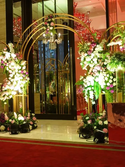 A series of golden arches adorned with cascading flowers creates a luxurious and grand walkway, making guests feel like they are entering a royal celebration.