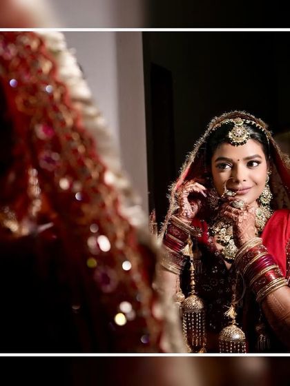 A beautiful shot of a bride looking at her reflection in the mirror, a classic and timeless moment during the getting-ready process.
