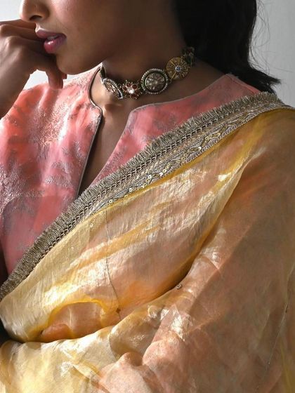 A close-up of a pink and yellow ombre tissue silk outfit, highlighting the delicate fabric and the intricate border.